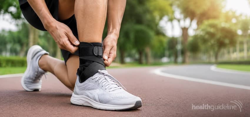 Runner adjusting a supportive ankle brace on a park trail while wearing running shoes for stability, comfort, and injury prevention during running.