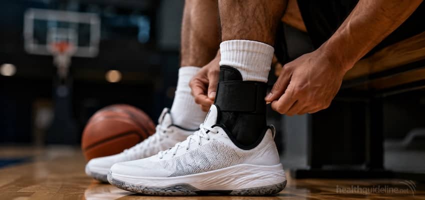 Basketball player tightening a supportive ankle brace before playing on an indoor basketball court.