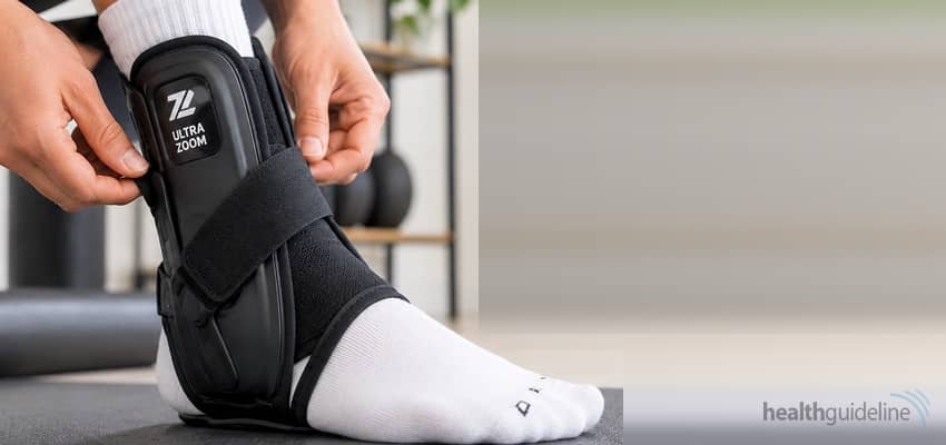 Person adjusting an Ultra Zoom ankle brace over a white sock in a bright home fitness setting for ankle support, stability, and recovery.