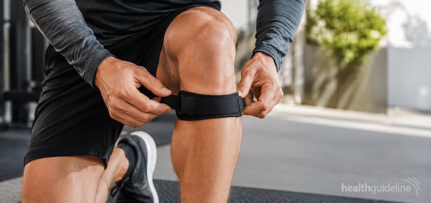 Man adjusting a black patellar tendon strap below the knee for knee pain support during exercise